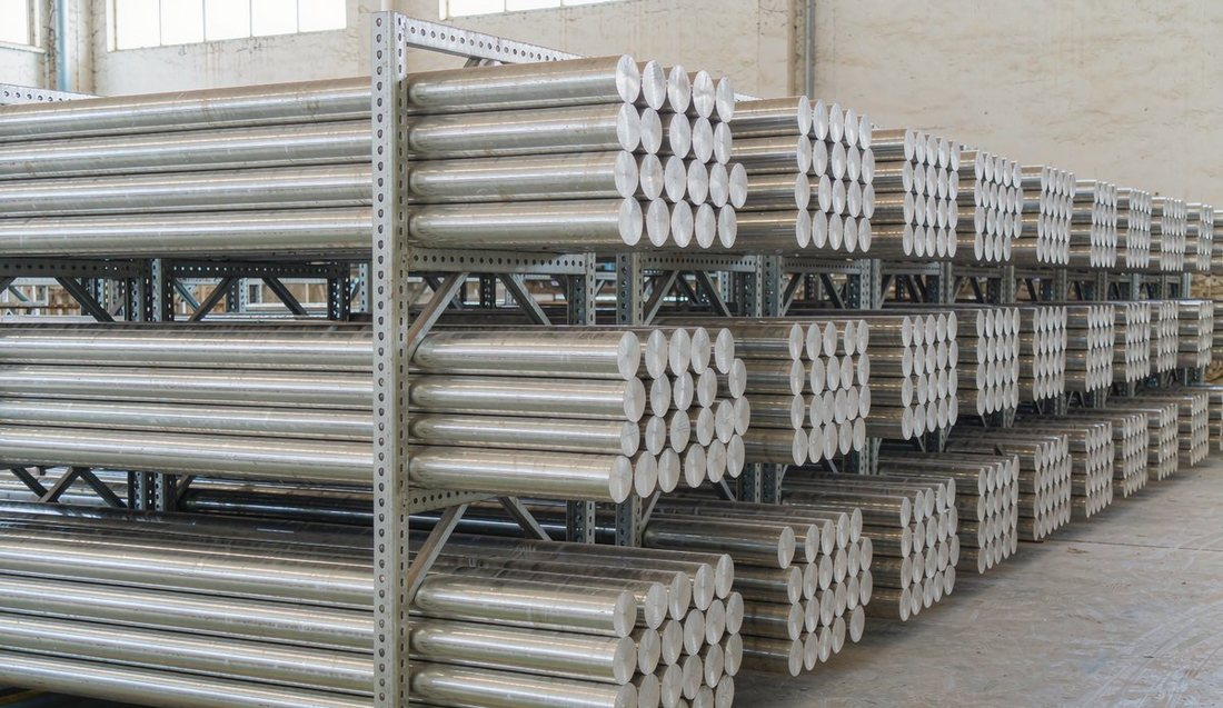 Stacked round 6061/6063 aluminum extrusion billets stored on racks in a warehouse