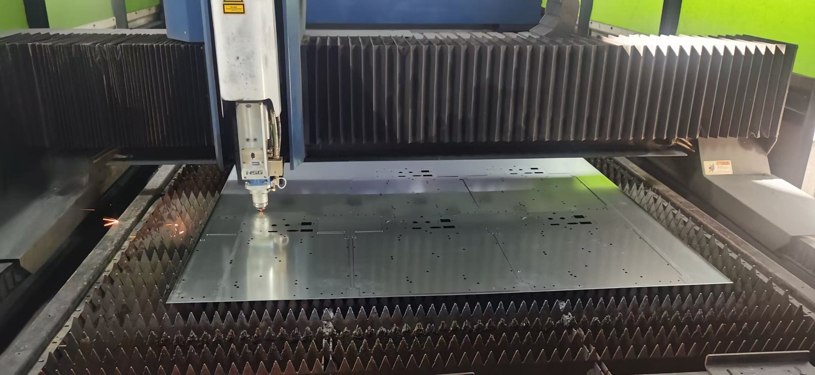 Close-up of the fiber laser head cutting nested parts